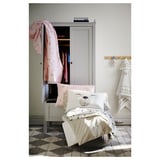 Childs room with white cabinet, checkered floor, small bed with white bear pillow, light pastel pink sheets, hanging towels.