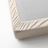 Fitted sheet with elastic edges, made from soft cotton, shown in cream and grey.