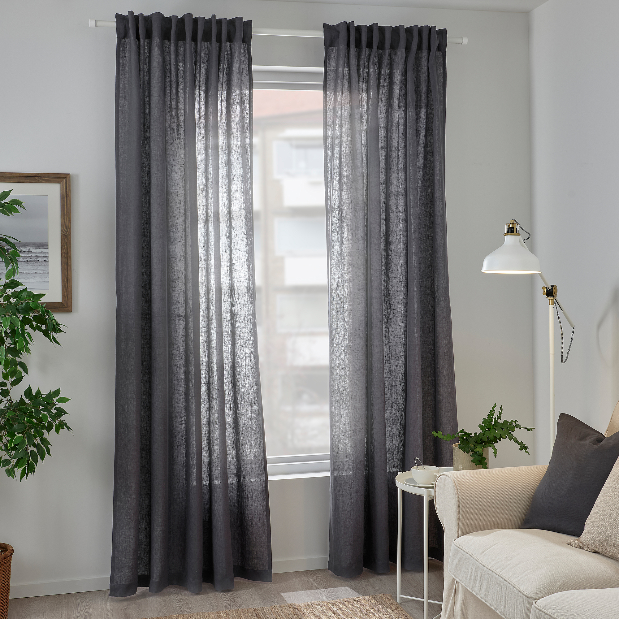 Modern living room with dark curtains, armchair, and plants.