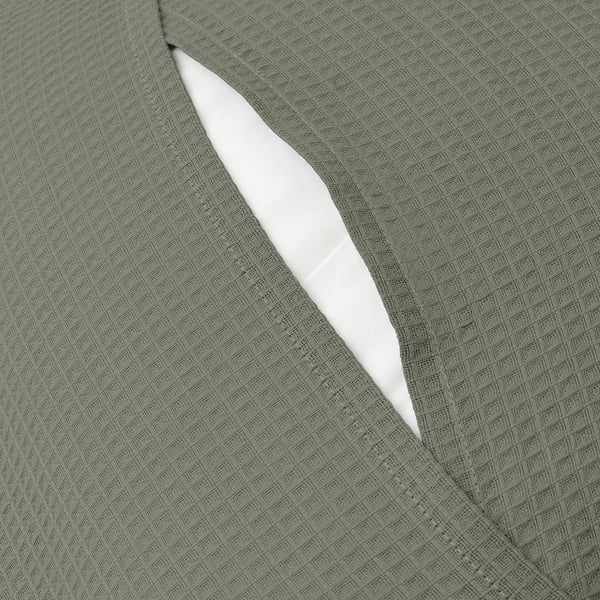 Close-up of a grey-green cushion cover with an envelope closure, showcasing its textured waffle pattern.
