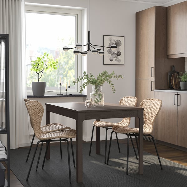 Modern dining room with EKEDALEN extendable table surrounded by woven chairs, sleek cabinetry, and greenery, featuring a stylish, minimalist design.
