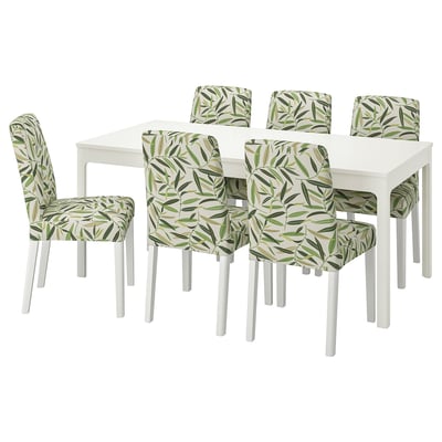 White dining table with 6 chairs, white with green leaf-patterned covers.