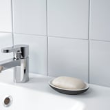 A modern bathroom sink with a chrome faucet and a small dish holding soap.