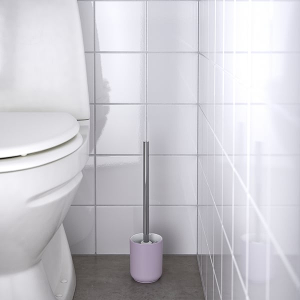 Purple toilet brush in holder, placed near white toilet, for easy cleaning.