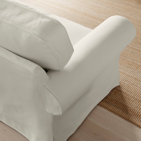 Close-up of plush white sofa cushions, well-stuffed and inviting, on patterned woven rug.