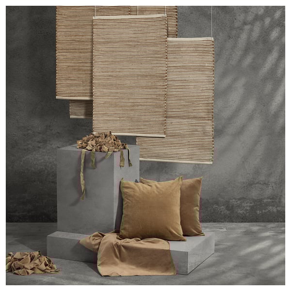 Modern interior decor with beige woven shades, brown pillows on grey blocks, textured grey wall.