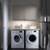 Modern laundry setup with ENHET washer & dryer, iron, detergents, and storage.