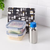 Black lunch bag with icons and food containers next to insulated water bottle on counter.