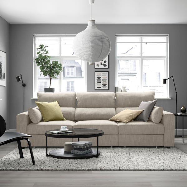 A modern living room with an ESKILSTUNA sofa, coffee table, rug, pendant light, and windows.