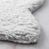 Soft, plush textured rug on a wooden floor. Close-up shows thick, fluffy yarns for warmth and comfort.