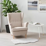 Cozy FÅRDRUP white rug under armchair by white side table & plant.