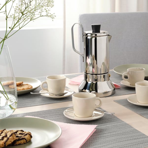 Table set with FÄRGKLAR cups, a coffee maker, and biscuits.
