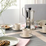 Table set with FÄRGKLAR cups, a coffee maker, and biscuits.