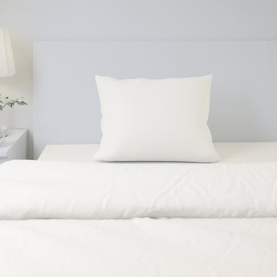 A minimalist bedroom setting with white cotton pillow and sheets, emphasizing comfort and natural material.