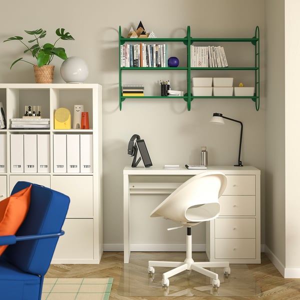 Modern home office with white desk, chair, green shelves, and blue seat.