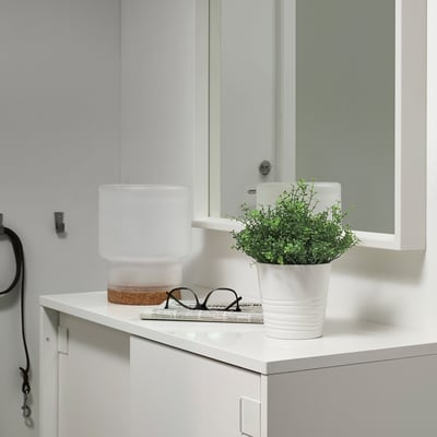 Modern bathroom with FEJKA plant, lamp, and newspaper.