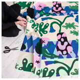 Person works on colorful fabric craft, scissors, pins nearby.