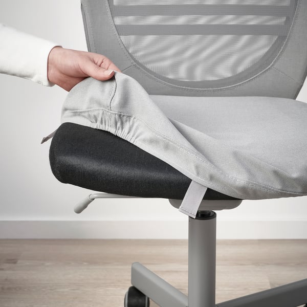 Person adjusting ergonomic office chair, FLINTAN model, featuring mesh back and removable seat cover.