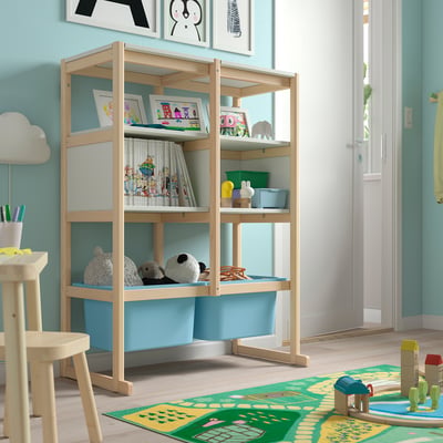 Wooden FLISAT storage unit with blue bins, toys, and books for kids room.