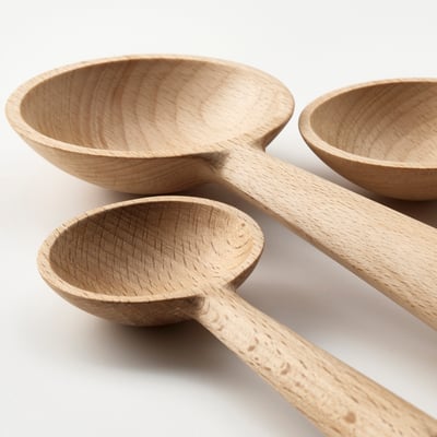 Three wooden spoons, light brown color, varying in size, placed side by side, displaying smooth and curved designs.