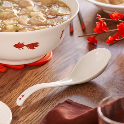 A white FÖSSTA soup spoon with a curved, easy-grip handle and subtle floral design for a classy look.