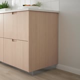Modern kitchen with bamboo veneer cabinets, clean handles, and tall unit beside tiled wall.