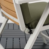 White outdoor chair with beige cushion showing elastic strap under seat for securing cushion.
