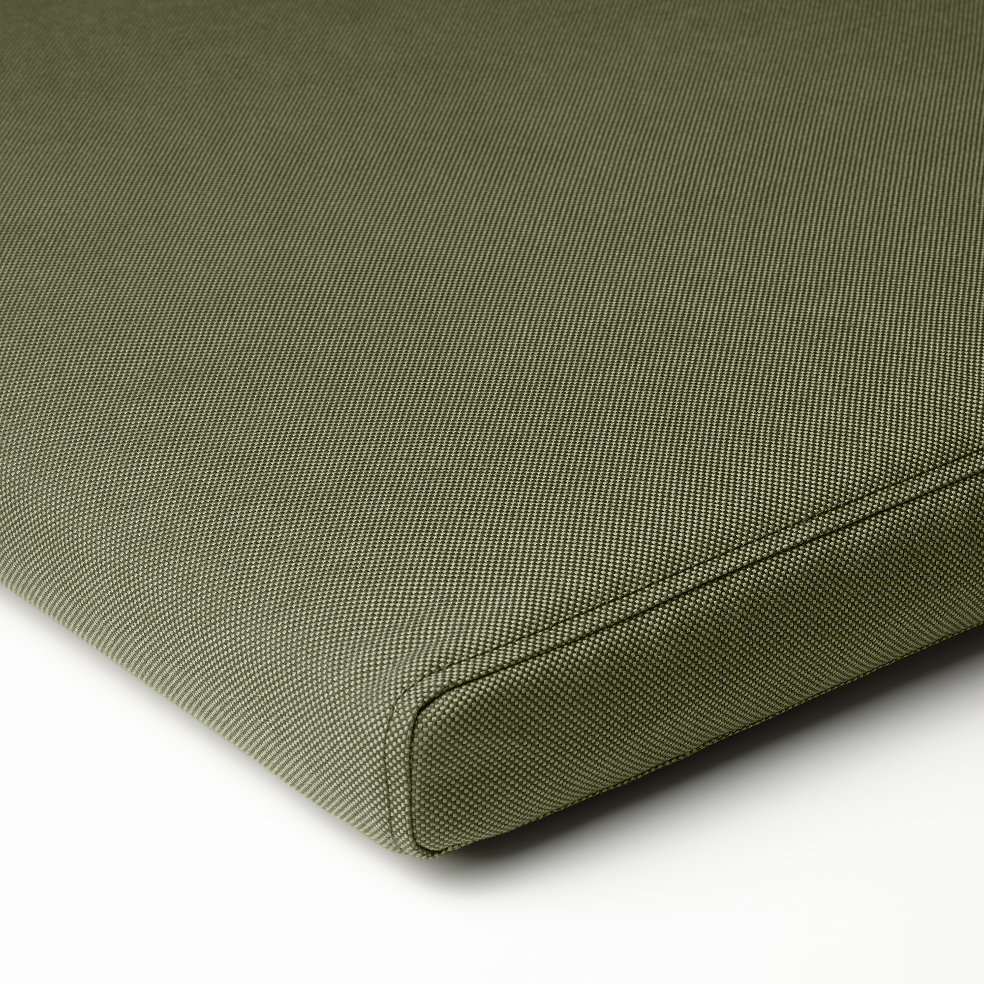 Green outdoor cushion close-up; smooth fabric, even stitching, quality design.