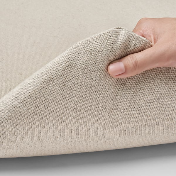 Person holding a beige zippered cushion, showcasing its easy-to-remove cover for washing.