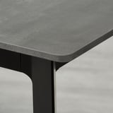 Close-up of extendable dining tables sleek, textured edge and sturdy black leg.