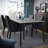 Modern dining area with extendable table, chairs, blue rug, bulbs, and curtains.