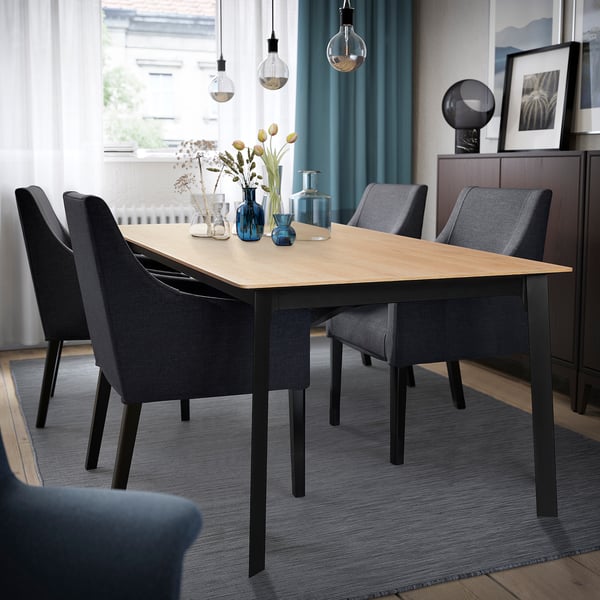 Modern GILLANDA dining table in light wood & black, extendable for 6-8, grey chairs, sleek legs, hanging lights.