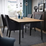 Modern GILLANDA dining table in light wood & black, extendable for 6-8, grey chairs, sleek legs, hanging lights.