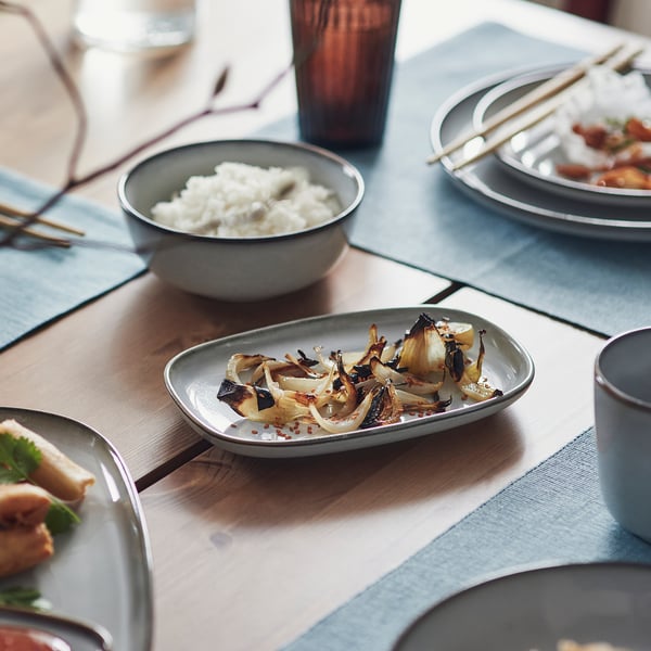 Dining table with gray stoneware, rice, grilled veggies, chopsticks.