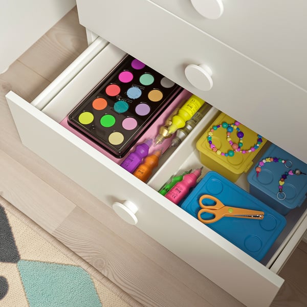 Open white drawer showcasing kids art supplies: paints, markers, beads, scissors, and storage boxes.