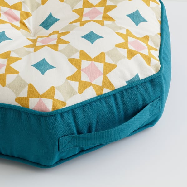 Octagonal floor cushion with yellow, white, pink, and blue star patterns. Soft cotton top, blue sides, and a carry handle.