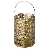 Gold GOKVÄLLÅ lantern, cylindrical shape with floral cutouts, handle on top, made of stainless steel.