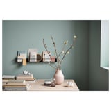 Modern living space with wood table, books, candles, and vase with flowers. Black and white shelf above with books and decor.