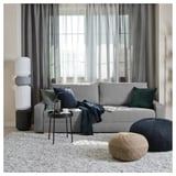 Modern living room with gray GRÄLVIKEN sofa, cushions, round poufs, side table, and tall floor lamp by window.