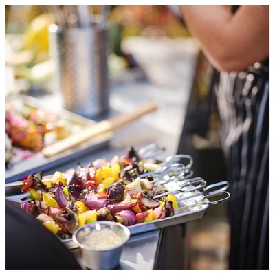 Shiny metal skewers with colorful veggies on grill.