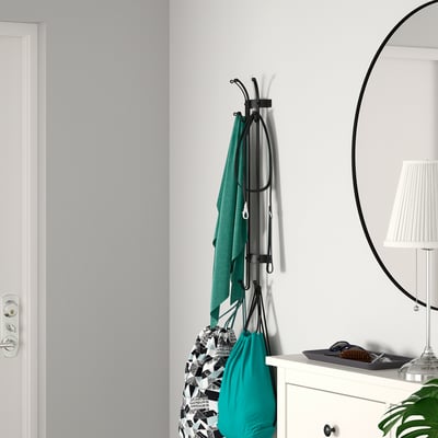 Gray wall-mount coat rack with green towels and bags, next to white dresser and round mirror.