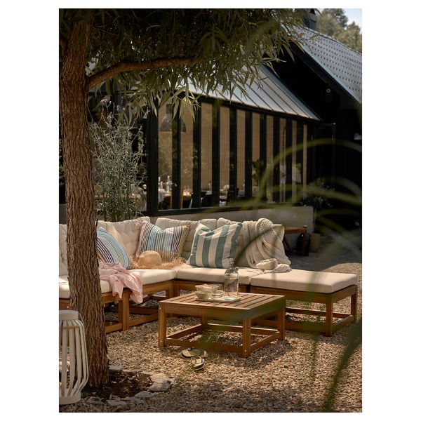 Outdoor scene with GULLBERGSÖ cushions on patio furniture under a tree.