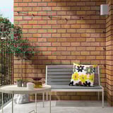 Gray cushion on bench with tea set and plant.