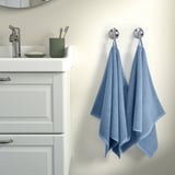 Bathroom with white sink, green accessories, chrome faucet, two blue GULVIAL towels on silver hooks.