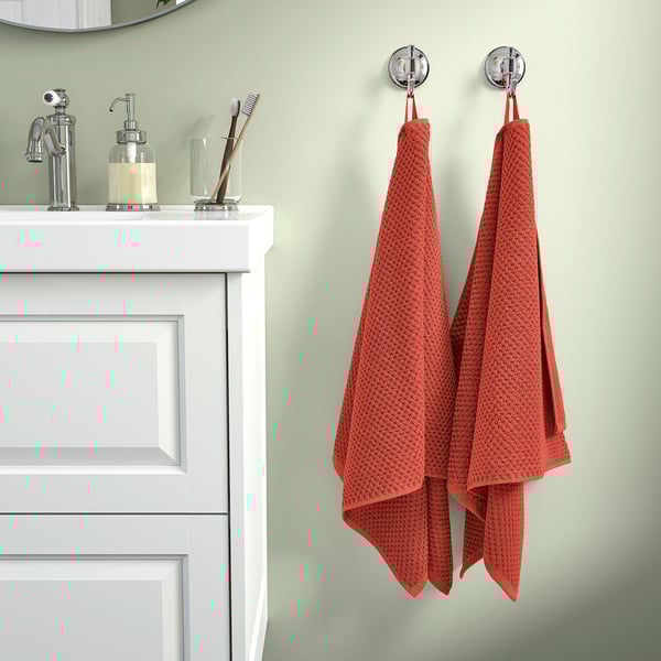 GULVIAL orange towels hang on modern bathroom hooks, white sink, chrome faucets, green wall - soft, fluffy, 100% cotton.