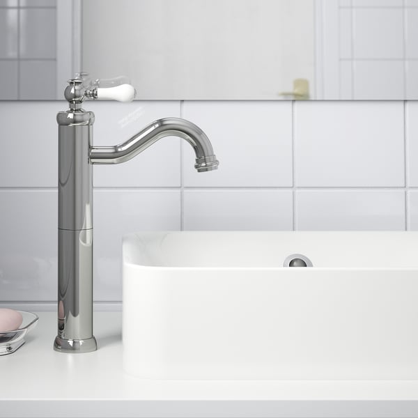 Modern chrome faucet with white ceramic lever and aerator, mounted on white bathroom countertop.