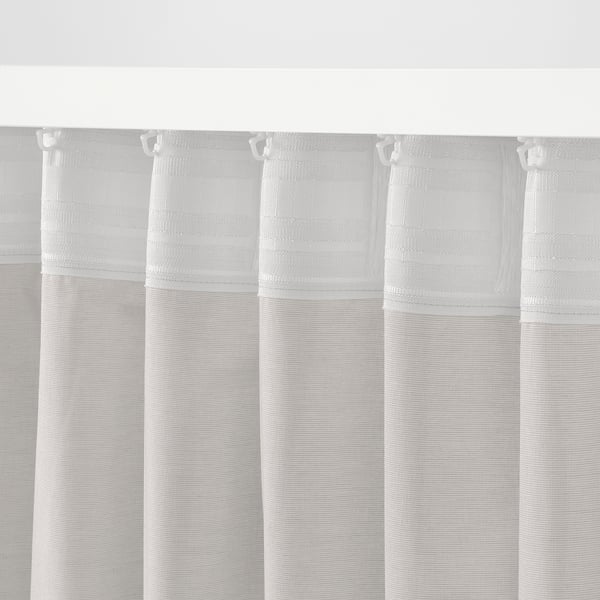 White sheer curtains with hooks, offering privacy and light diffusion.