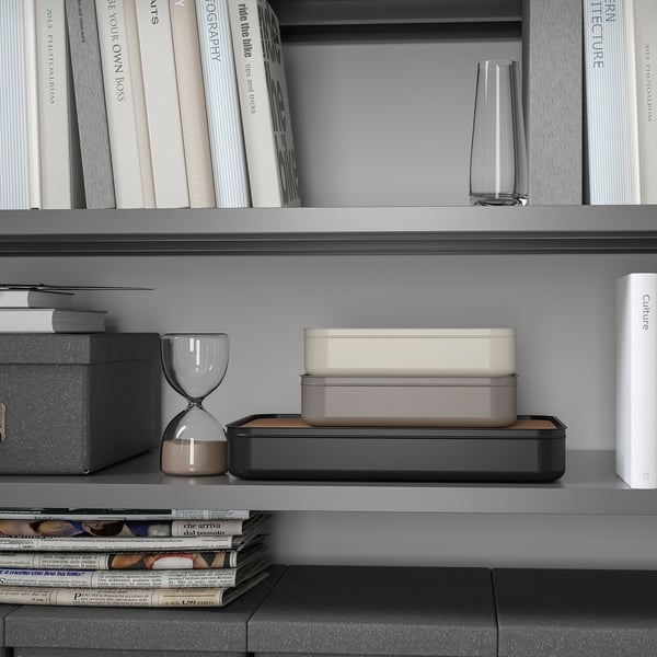 Bookshelf with HARVMATTA organizer, small items, hourglass, and a stack of magazines.