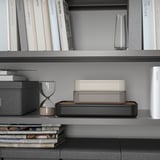 Bookshelf with HARVMATTA organizer, small items, hourglass, and a stack of magazines.