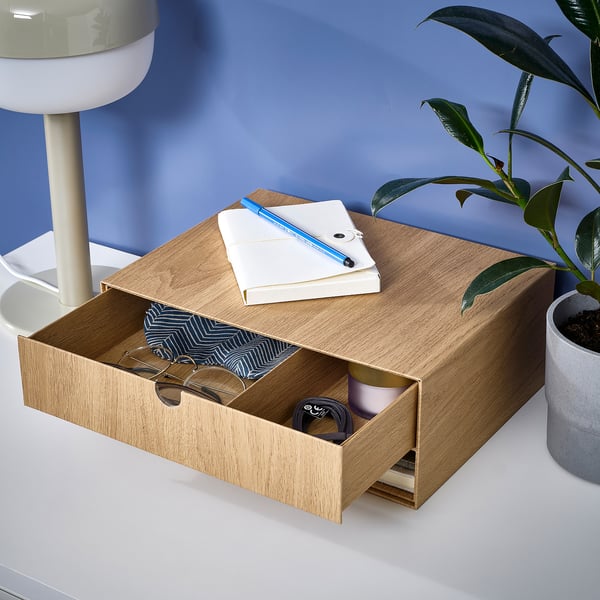 Desk organizer with drawer, compartments, and open top. On desk with plant and lamp.